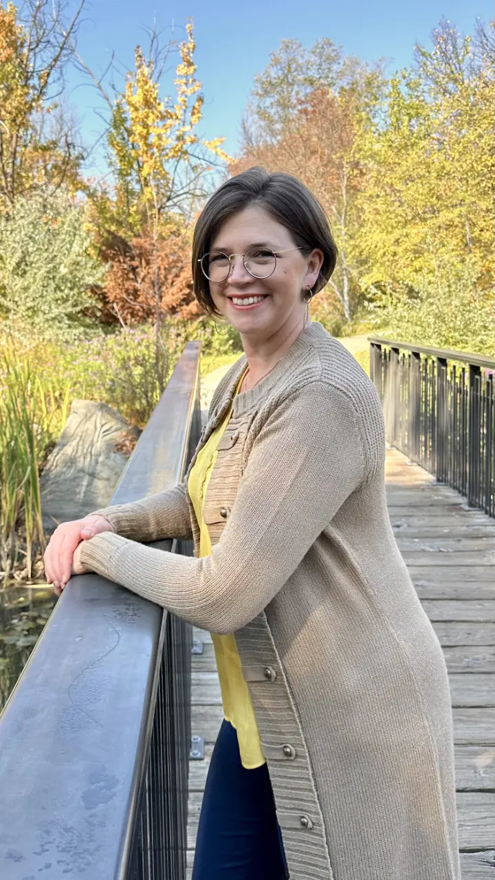 Headshot of Sarah Massie standing on a wooden footbridge in an autumn scene.